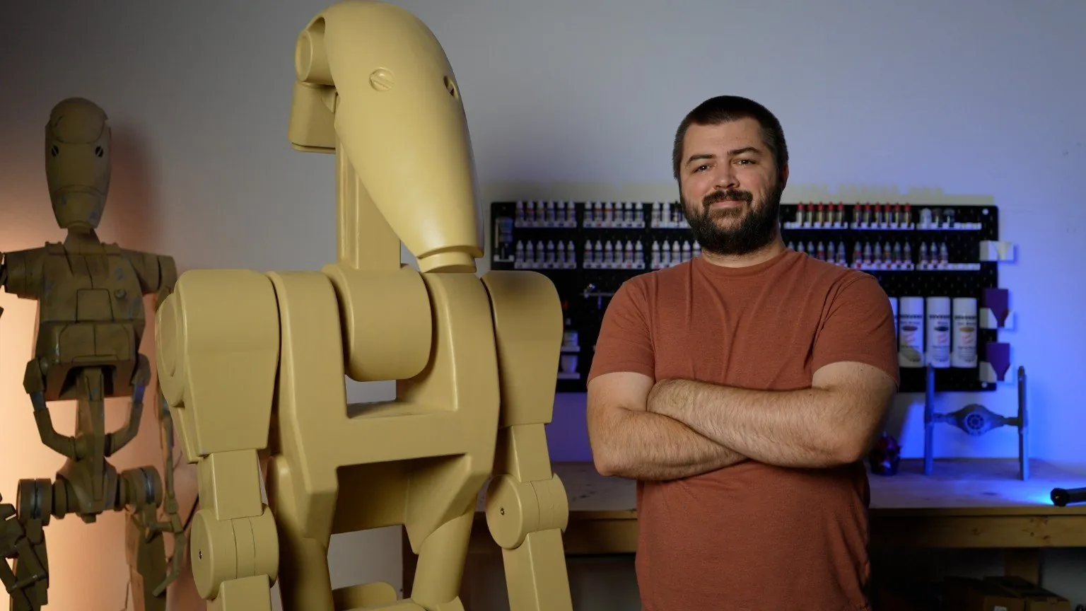 Mike, standing with arms crossed next to two life-size 3D-printed B1 battle droids in his workshop